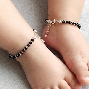 May include: A pair of anklets featuring small, round, black beads interspersed with tiny, polished silver-toned metal spacers. Each anklet includes a delicate silver-toned metal chain with a lobster claw clasp and an adjustable extender link.