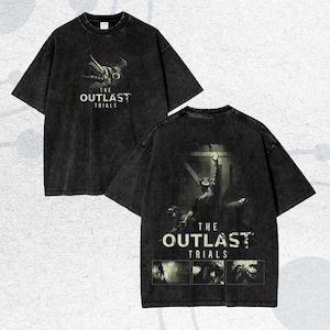 Könnte beinhalten: Schwarzes T-Shirt mit einem Grafikdruck von "THE OUTLAST TRIALS." Die Vorderseite zeigt ein Kreaturendesign, während die Rückseite eine Figur mit dem Titel des Spiels und zusätzlichen Bildern zeigt. Das T-Shirt hat einen Vintage-Look.