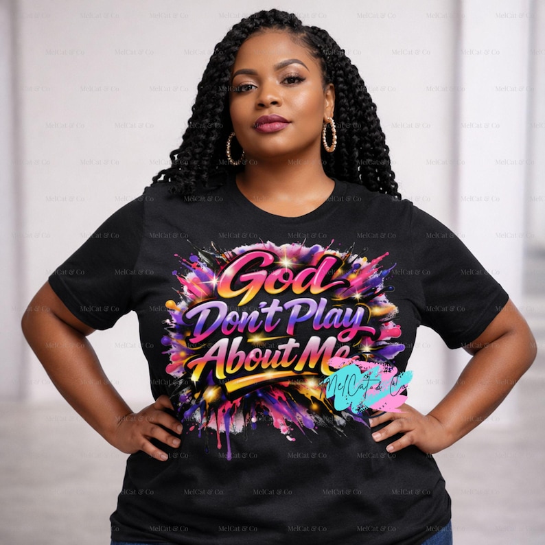 May include: Black t-shirt with the text "God Don't Play About Me" in a colorful, stylized design. The design features a burst of pink, purple, yellow, and blue colors. The shirt is short-sleeved.