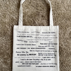 Può includere: Una borsa tote in tela bianca con una collezione di frasi e citazioni stampate in nero in vari caratteri. Il testo include righe come Release the fetus, Sapphire guys, Mexican, Salsa, Yes, e I need to calm down. Everything is fine, I'm an adult.