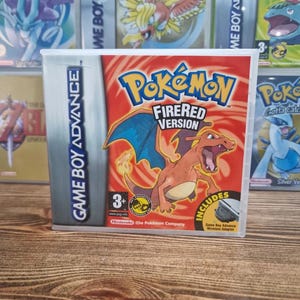 Puede incluir: Cartucho de videojuego de Game Boy Advance para Pokémon FireRed Version. La caja del juego es roja y presenta una ilustración de Charizard. La caja incluye el texto "Game Boy Advance" y "Includes Game Boy Advance Wireless Adapter."