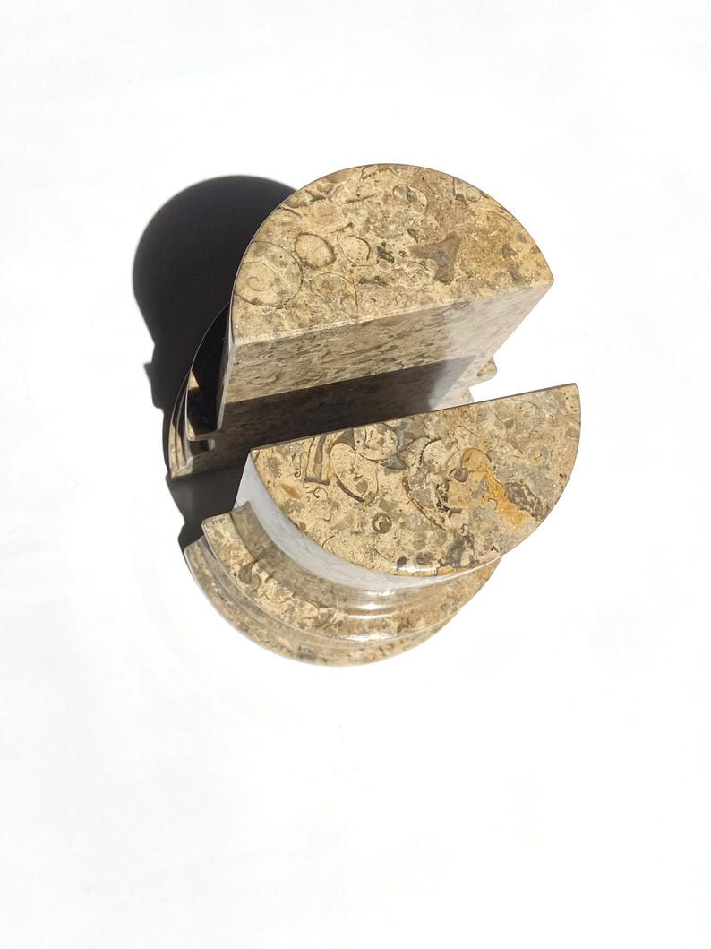 Puede incluir: Un par de sujetalibros semicirculares hechos de piedra caliza fosil&iacute;fera pulida. Cada pieza presenta una superficie moteada en tonos beige y bronceado con inclusiones f&oacute;siles org&aacute;nicas visibles, borde superior redondeado y base plana.