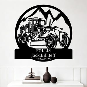 May include: Black metal wall art depicting a grader machine design with a mountain background. The name "FOLLIS" and the names "Jack, Bill, Jeff" are displayed below the grader, along with the years "1946-2025".