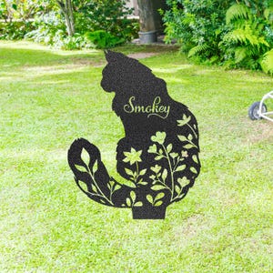 May include: A black metal cat silhouette garden stake with floral cutouts. The cat's name, "Smokey," is scripted across the body. The stake is designed to be placed in a garden or yard, adding a decorative touch.