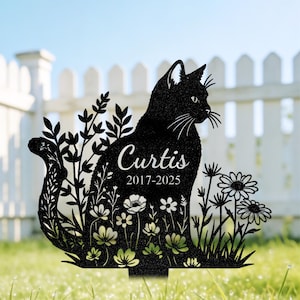 Könnte beinhalten: Ein schwarzer Gartenstecker aus Metall mit der Silhouette einer sitzenden Katze, umgeben von Blumenmotiven. Der Name Curtis und die Jahreszahlen 2017-2025 sind in weißer Schrift auf den Körper der Katze graviert, die inmitten von Blumen steht.