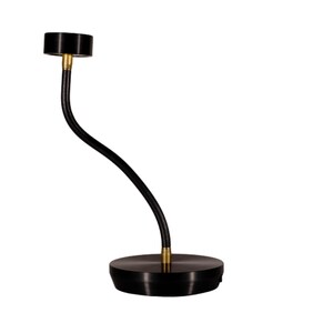 Peut inclure: Un bougeoir en métal noir avec une tige incurvée et élancée et une base circulaire. Le haut du support est également circulaire, conçu pour contenir une bougie. Le support a un accent en laiton.