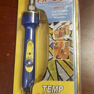 Könnte beinhalten: Blau-gelber HAKKO FX-601 Temperaturregel-Lötkolben in Originalverpackung. Die Verpackung enthält den Text "IDEAL FOR: Large Components, Battery Terminals, Stained Glass" und "TEMP CONTROL". Der Temperaturbereich beträgt 240° - 540°C.