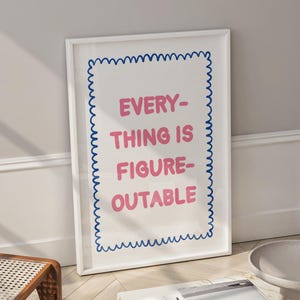 May include: A framed art print with the text "EVERYTHING IS FIGURE-OUTABLE" in pink, outlined with a blue wavy border. The print is displayed in a bright, modern living space with a white marble coffee table and wooden furniture.