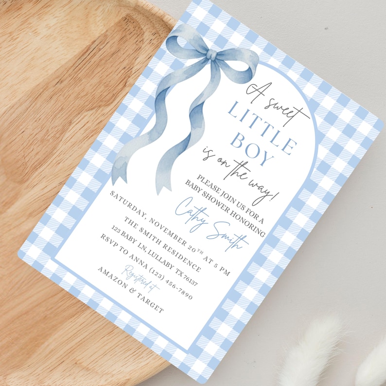 May include: A baby shower invitation with a blue gingham pattern. The text reads "A sweet LITTLE BOY is on the way!" and includes event details like date, time, location, and RSVP information. A blue ribbon bow adorns the top of the invitation.