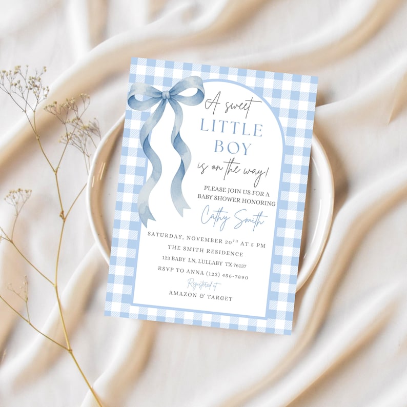 May include: A baby shower invitation with a blue gingham pattern and a watercolour bow. The text reads "A sweet LITTLE BOY is on the way!" and includes event details. Registered at Amazon & Target.