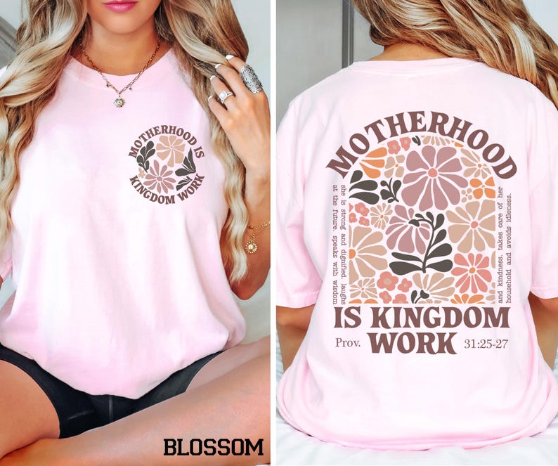 May include: A pale pink t-shirt featuring the text "MOTHERHOOD IS KINGDOM WORK" and a floral design. The back of the shirt has the same text and design. The shirt is a blossom colour.