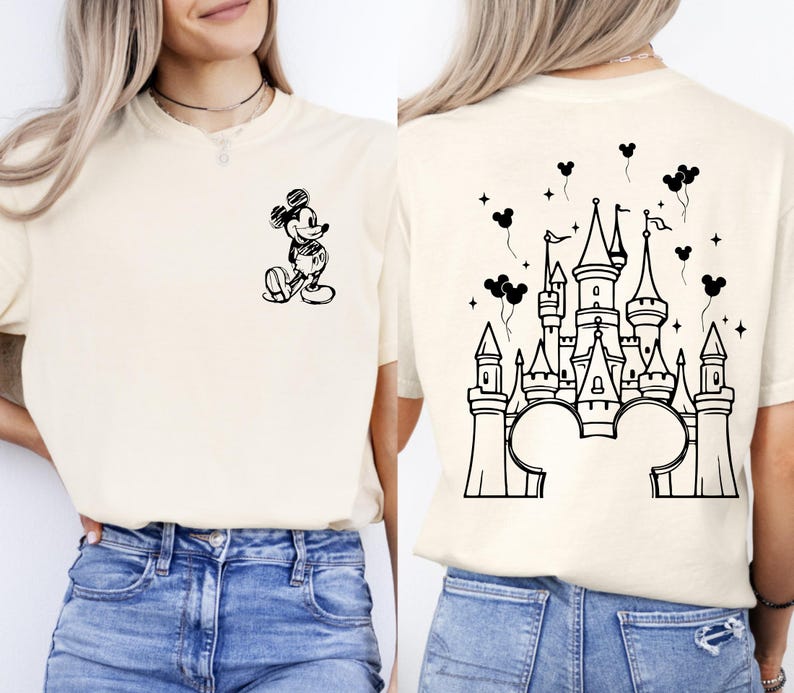 Puede incluir: Camiseta color crema con un boceto negro de Mickey Mouse en la parte delantera y un dise&ntilde;o de castillo en la parte trasera. El dise&ntilde;o del castillo incluye orejas de Mickey Mouse en la base, con globos y estrellas.