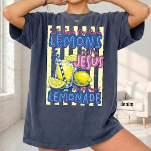 May include: Denim blue t-shirt with a graphic of a glass of lemonade, lemons, and the text "Life Gave Me Some Lemons But My Jesus He Be Makin' Lemonade". The design has yellow and white stripes.