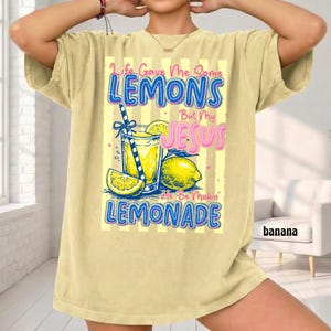 May include: A light yellow t-shirt with the text "Life Gave Me Some Lemons But My Jesus He Be Makin' Lemonade." The graphic includes a glass of lemonade, lemons, and a straw.