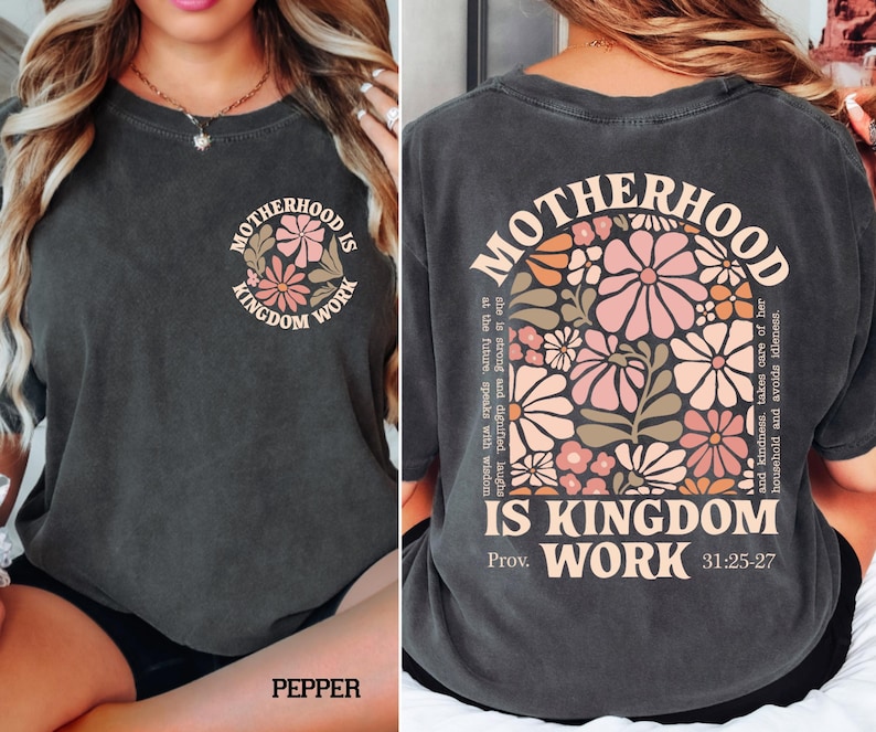 May include: Dark grey t-shirt with the words "MOTHERHOOD IS KINGDOM WORK" and a floral design. The back of the shirt has the same text and a larger floral design with a quote from Proverbs 31:25-27.