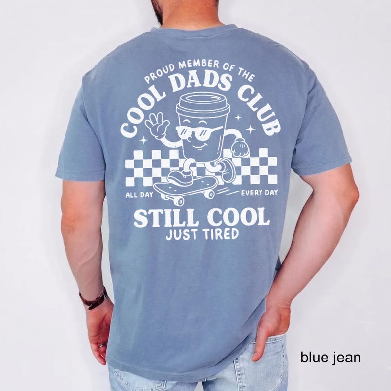 Pu&ograve; includere: T-shirt blu a maniche corte con grafica bianca di una tazza di caff&egrave; su uno skateboard. Il testo recita "PROUD MEMBER OF THE COOL DADS CLUB" e "STILL COOL JUST TIRED".
