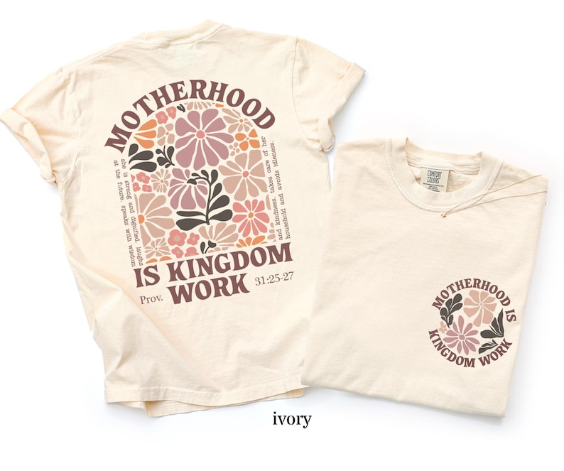 May include: Two ivory-coloured t-shirts. One has a floral design and the text "MOTHERHOOD IS KINGDOM WORK" on the back. The other has the same design on the front. The shirts are made of a soft material.