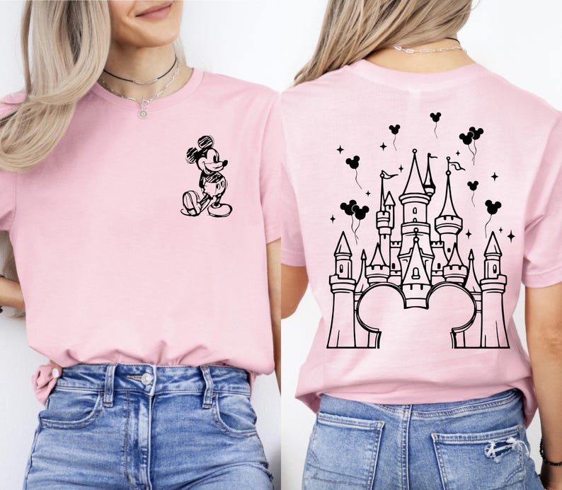Puede incluir: Camiseta rosa claro con un boceto negro de Mickey Mouse en la parte delantera y un dise&ntilde;o de castillo en la parte trasera. El dise&ntilde;o del castillo incluye orejas de Mickey Mouse y globos.