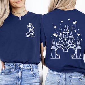 Puede incluir: Camiseta azul marino con un gr&aacute;fico blanco de Mickey Mouse en la parte delantera y un dise&ntilde;o de castillo blanco en la parte trasera. El dise&ntilde;o del castillo incluye orejas de Mickey Mouse, globos y estrellas. La camiseta es de material suave.