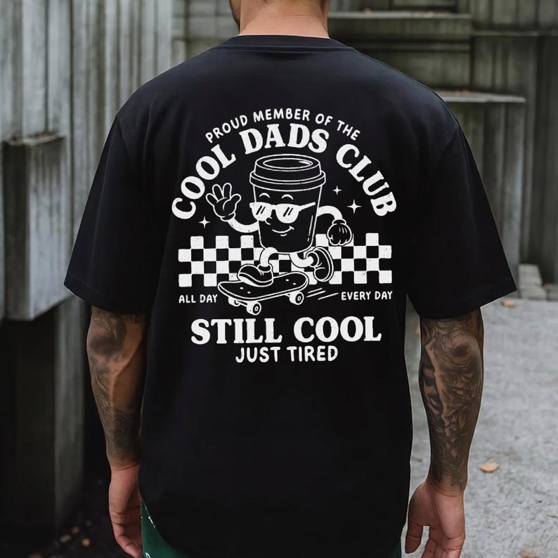 Pu&ograve; includere: T-shirt nero con grafica bianca di una tazza di caff&egrave; con occhiali da sole e che fa skateboard. Il testo recita "PROUD MEMBER OF THE COOL DADS CLUB" e "STILL COOL JUST TIRED".