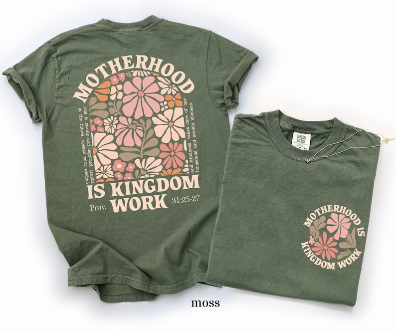 May include: Two moss-green t-shirts. One features the text "MOTHERHOOD IS KINGDOM WORK" with floral graphics. The other shirt has the same text and floral design on the front pocket. The text "Prov. 31:25-27" is also visible.