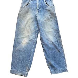 May include: Light blue denim jeans with a faded wash and a relaxed fit. The jeans have a classic five-pocket design, a button and zipper closure, and a straight leg. The jeans are vintage and show signs of wear.