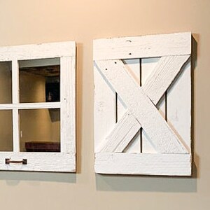 May include: Two white painted wooden wall decor pieces. One is a window frame with a pane of glass and the other is a barn door style with an X design.