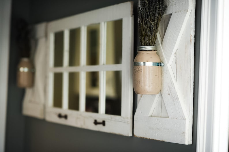 May include: Two white painted wooden window frames with glass panes, one with a mason jar filled with dried lavender and a metal band, mounted on a gray wall.