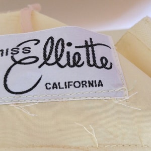 Puede incluir: Una etiqueta blanca con texto negro que dice "miss Elliette CALIFORNIA".