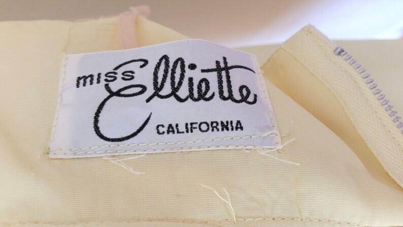 Puede incluir: Una etiqueta blanca con texto negro que dice "miss Elliette CALIFORNIA".