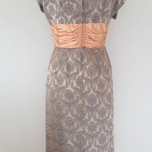May include: A vintage dress with a gray and peach brocade pattern. The dress has a fitted bodice and a full skirt. It features a peach satin sash around the waist.