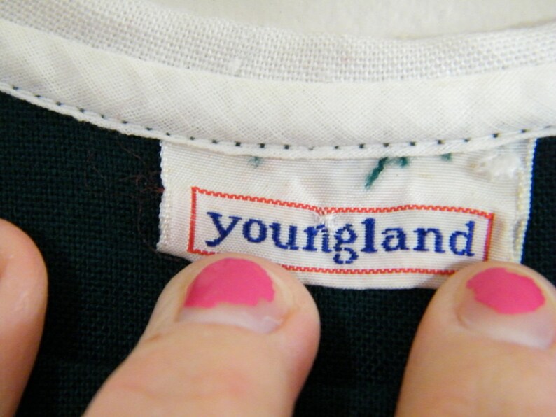 Puede incluir: Primer plano de una camisa verde oscuro con cuello blanco y una etiqueta blanca que dice "youngland" en letras azules.