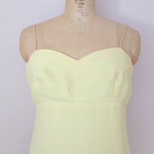 Puede incluir: Un vestido amarillo p&aacute;lido sin mangas con escote de coraz&oacute;n. El vestido est&aacute; en un maniqu&iacute;.