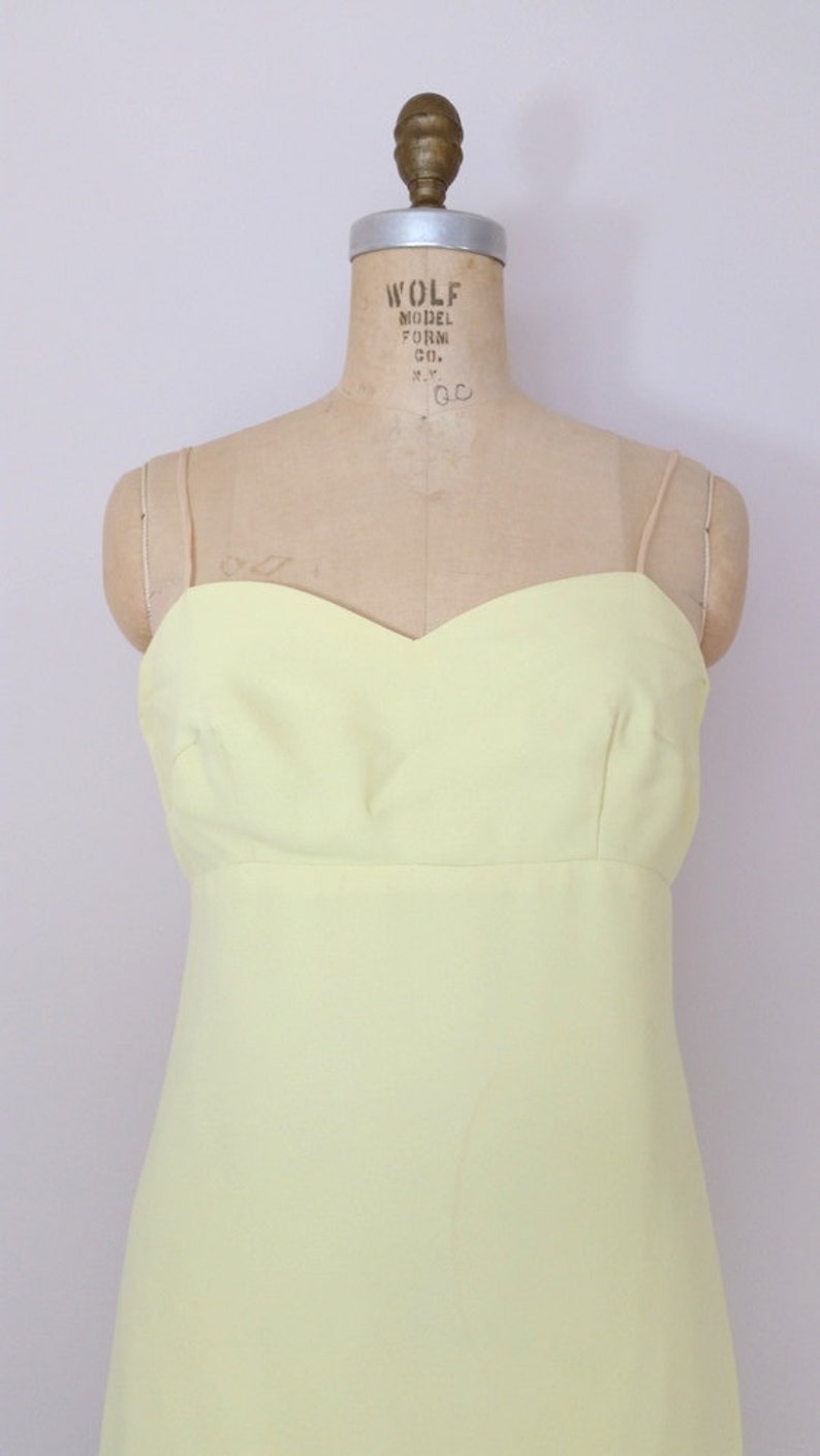 Puede incluir: Un vestido amarillo p&aacute;lido sin mangas con escote de coraz&oacute;n. El vestido est&aacute; en un maniqu&iacute;.