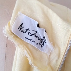 May include: A close-up of a yellow fabric label with black text that reads "Nat Jurist Chicago".