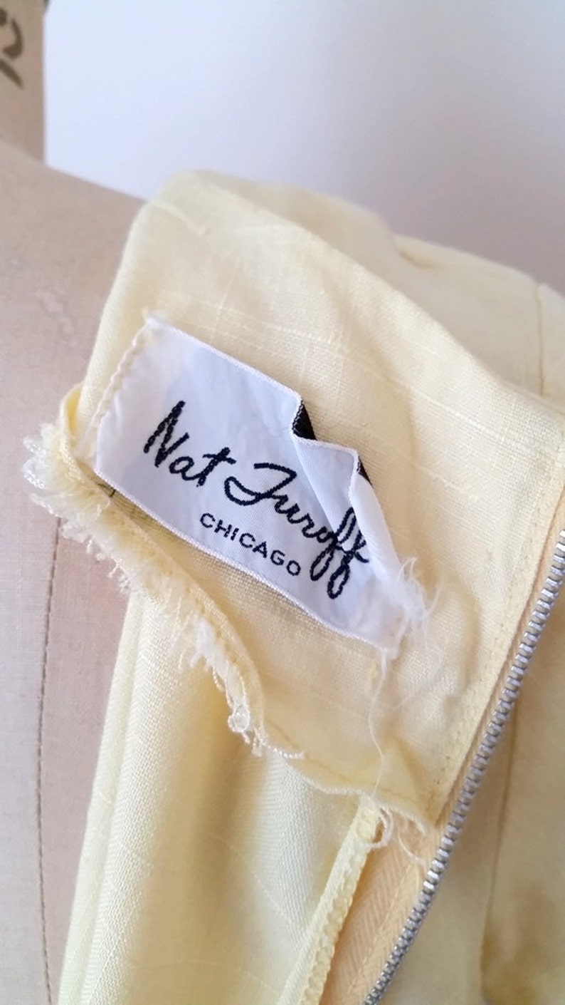 May include: A close-up of a yellow fabric label with black text that reads "Nat Jurist Chicago".