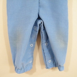 Op de afbeelding: Een lichtblauwe broek van corduroy met witte knopen.
