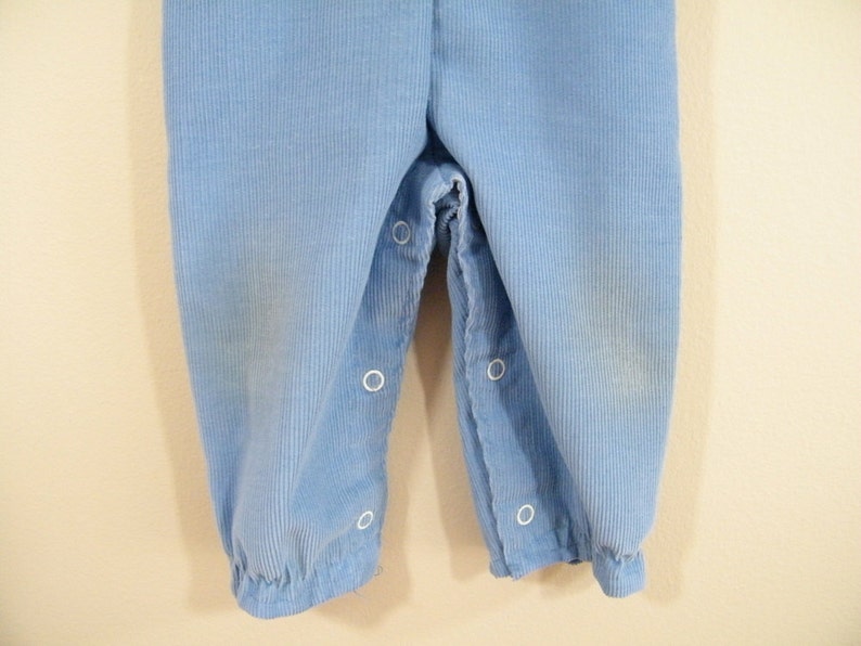 Op de afbeelding: Een lichtblauwe broek van corduroy met witte knopen.