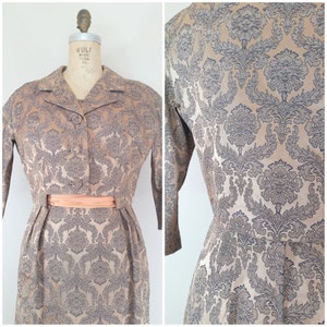 May include: A vintage two-piece dress set in a beige and gray damask pattern with a peach-colored sash. The dress has a fitted bodice and a full skirt.