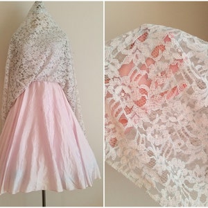 May include: A pink tulle skirt with a white lace overlay. The lace is delicate and has a floral pattern.
