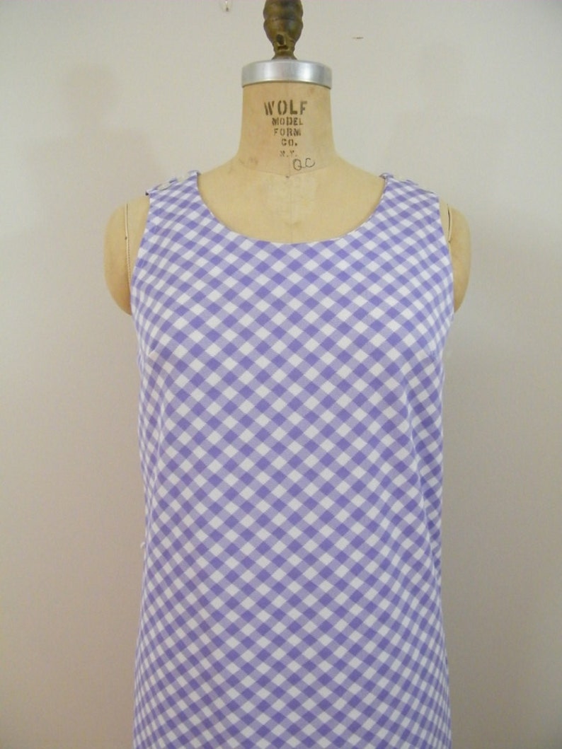 May include: A sleeveless dress with a white and purple gingham pattern.