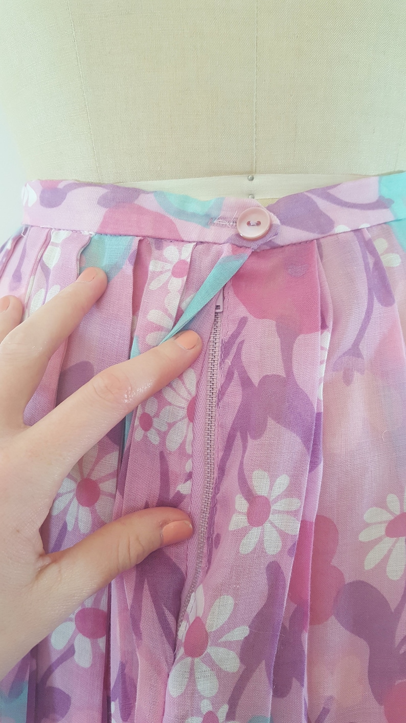 May include: A pink and purple floral skirt with a zipper closure and a single button at the waist.