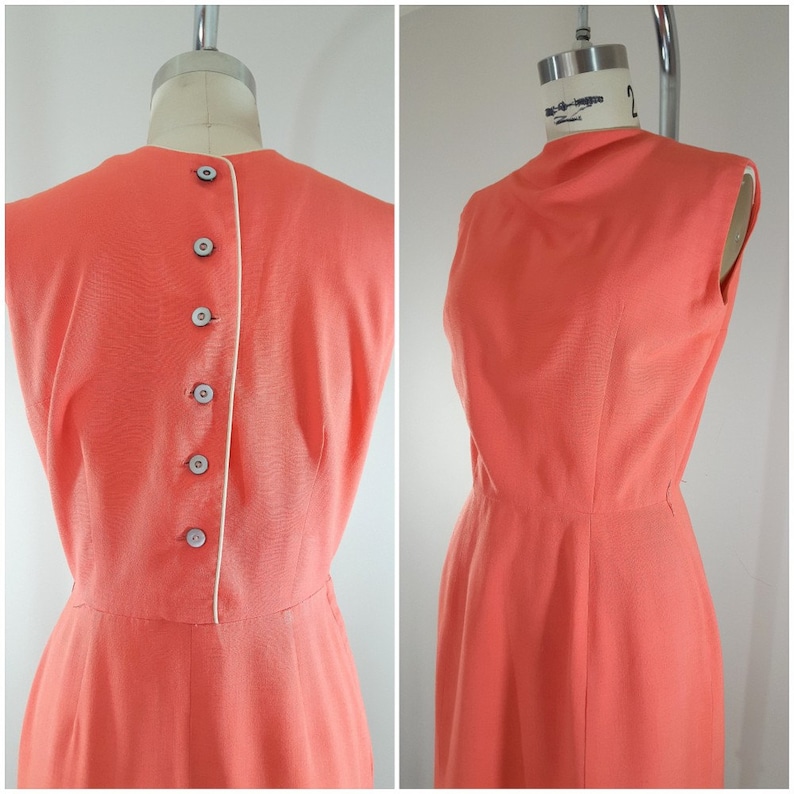 Puede incluir: Un vestido coral sin mangas con un ribete blanco en la espalda y una fila de botones. El vestido tiene un corpi&ntilde;o ajustado y una falda ligeramente acampanada.