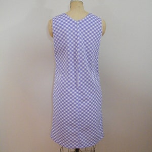 May include: A sleeveless dress with a white and purple gingham pattern. The dress is fitted and has a straight skirt.