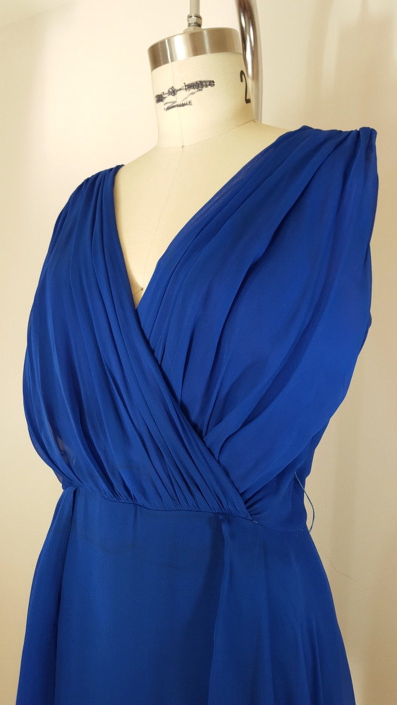 Puede incluir: Un vestido maxi sin mangas azul real con escote en V y falda fluida.