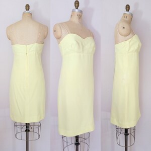 Puede incluir: Un vestido sin mangas de color amarillo p&aacute;lido con un escote de coraz&oacute;n. El vestido es entallado y tiene una falda recta. Se muestra sobre un fondo blanco.