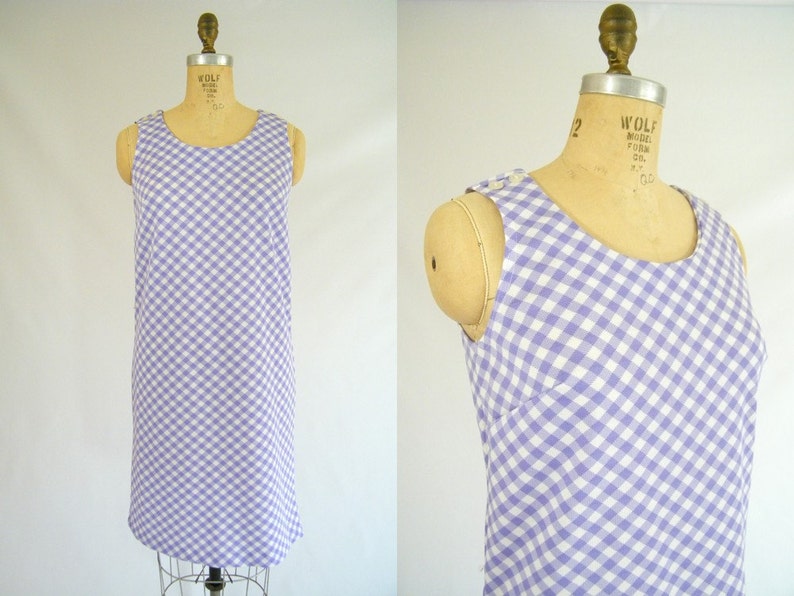 May include: A sleeveless dress with a white and purple gingham pattern. The dress has a scoop neck and a straight silhouette.
