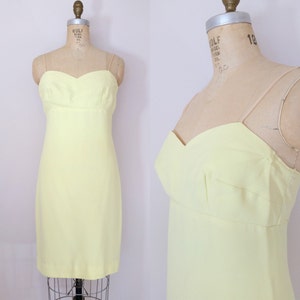 Puede incluir: Un vestido sin mangas de color amarillo p&aacute;lido con un escote de coraz&oacute;n. El vestido es entallado y tiene una falda recta.