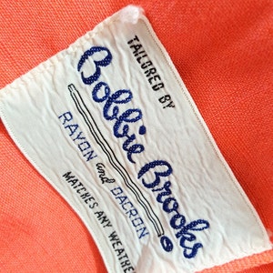 Puede incluir: Etiqueta blanca con texto azul que dice "Tailored by Bobbie Brooks Rayon and Dacron Matches Any Weather"