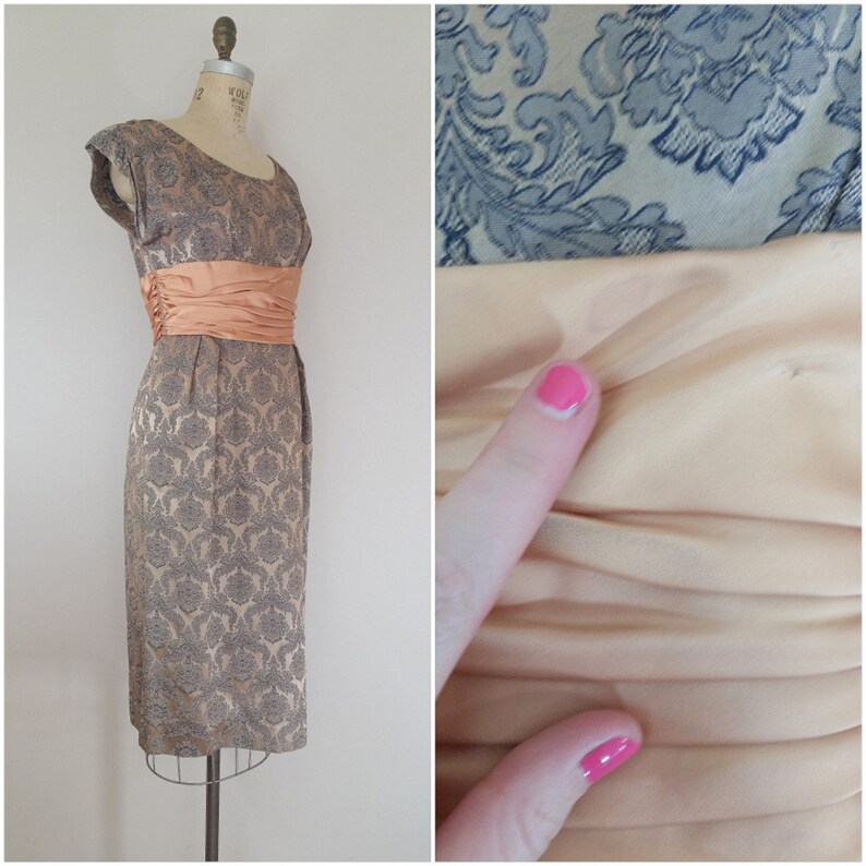 May include: A vintage 1950s or 1960s gray and silver brocade dress with a peach satin sash. The dress has a fitted bodice and a full skirt. The sash is tied in a bow at the back.